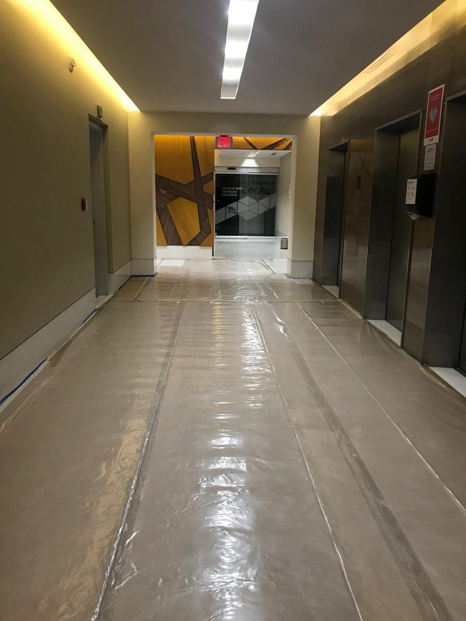 Pasillo de elevadores con piso protegido durante remodelación