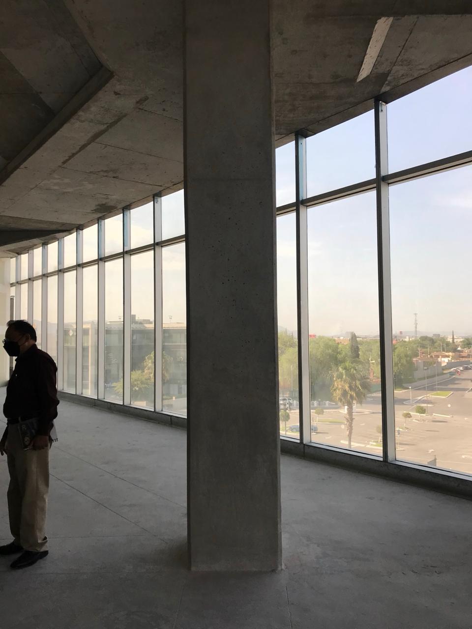 Planta libre en obra gris con columnas de concreto y muro cortina