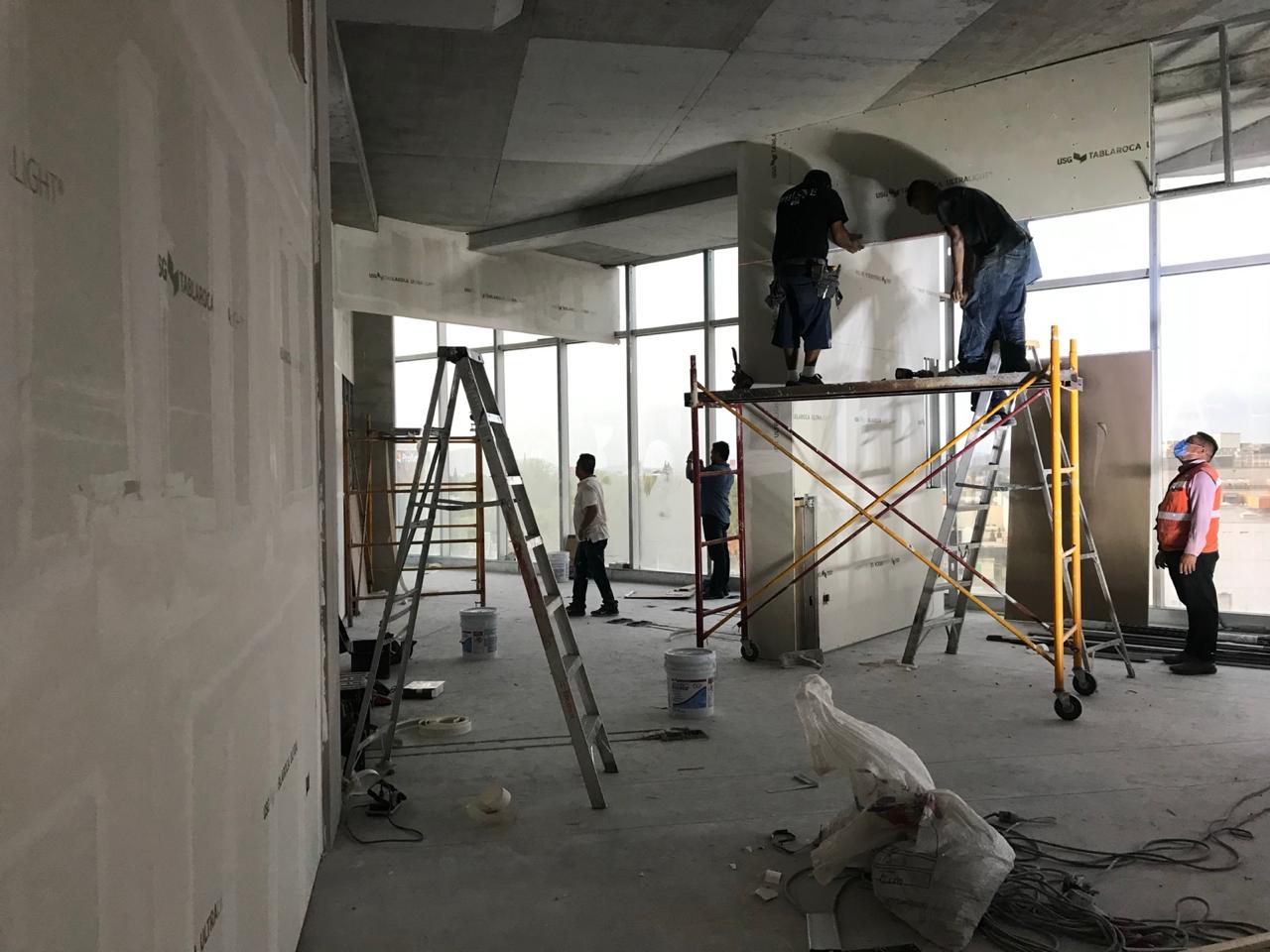Trabajos en andamio junto al muro cortina durante acabados interiores
