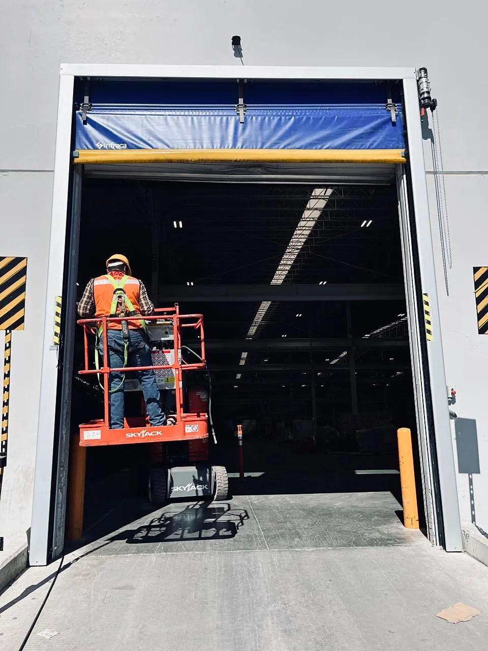 Instalación de una cortina de acceso industrial desde plataforma de tijera