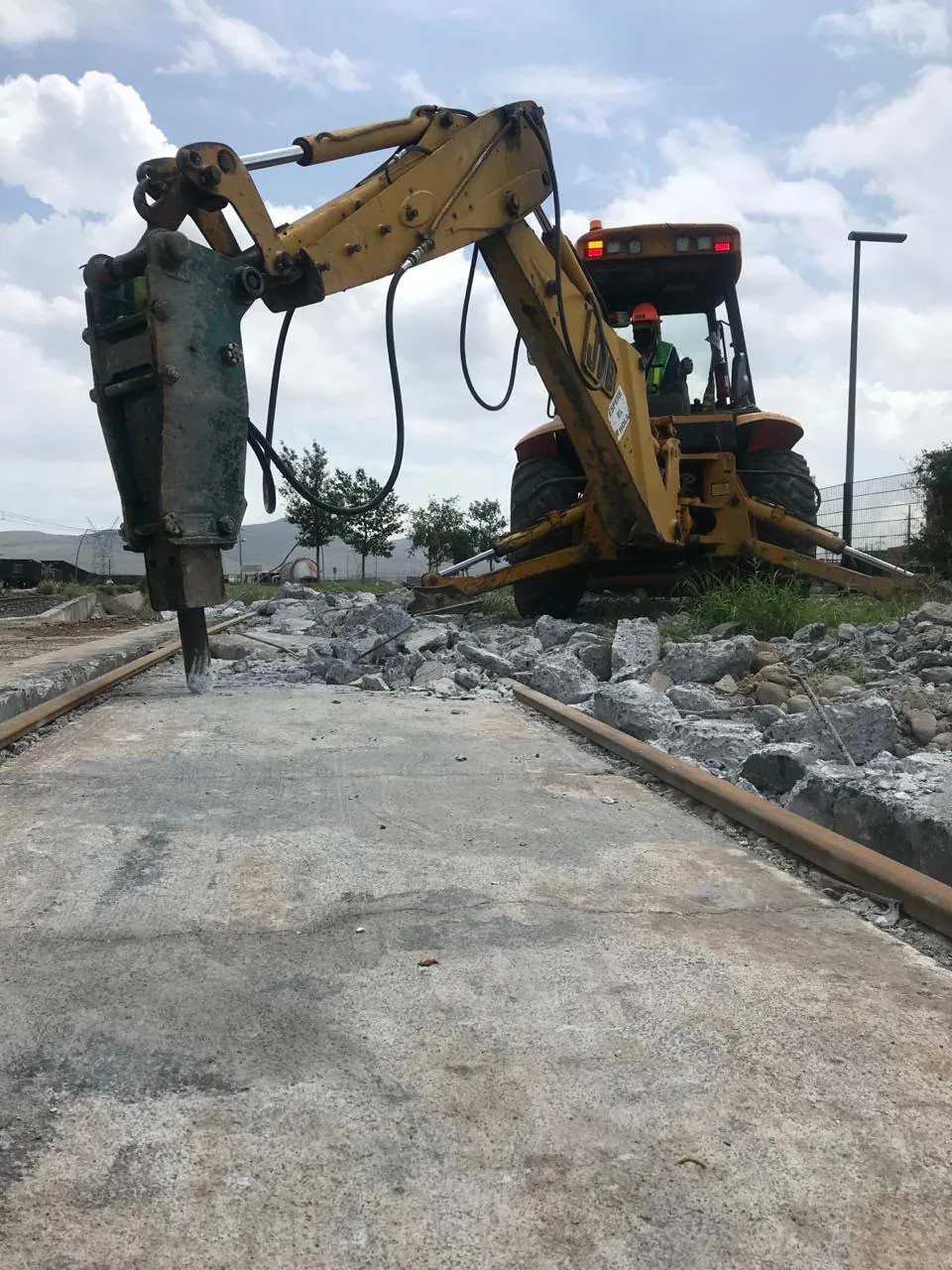 Retroexcavadora con martillo hidráulico demoliendo una losa de concreto